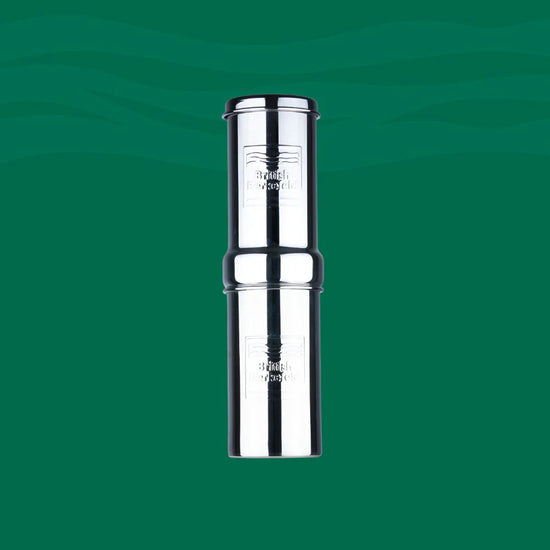 A shiny British Berkefeld 1-liter stainless steel gravity system by American Reserves stands against a green backdrop, featuring a cylindrical design and branding. It uses an Ultra Sterasyl ceramic filter for effective purification.
