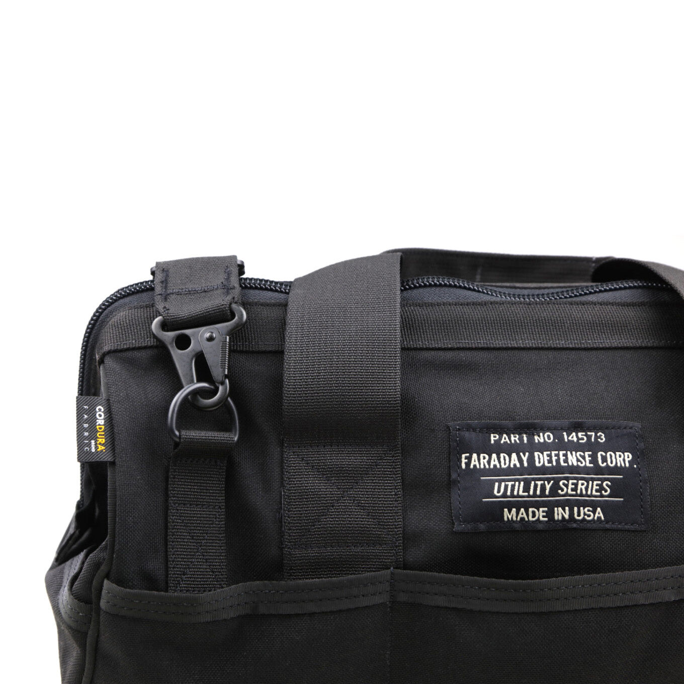 Close-up of a black CORDURA® Utility Bag Medium by American Reserves featuring a zipper, clip, and label reading Faraday Defense Corp. Utility Series Made in USA. This signal-blocking pouch keeps your items secure and protected.