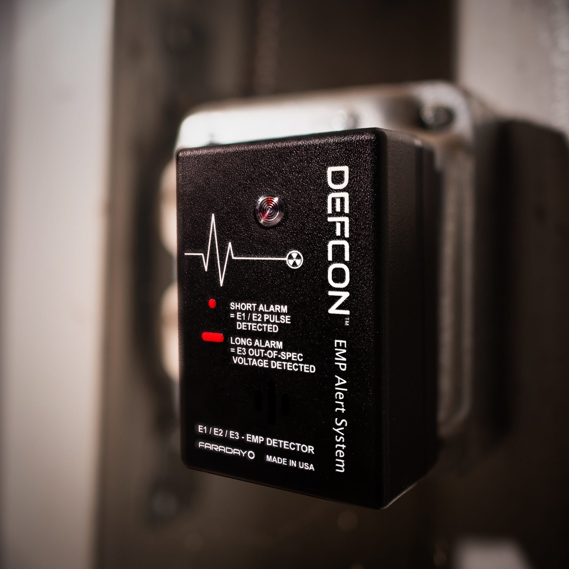 Close-up of an American Reserves DEFCON™ EMP Alert System installed on a wall, showcasing electromagnetic pulse detection indicators and text.
