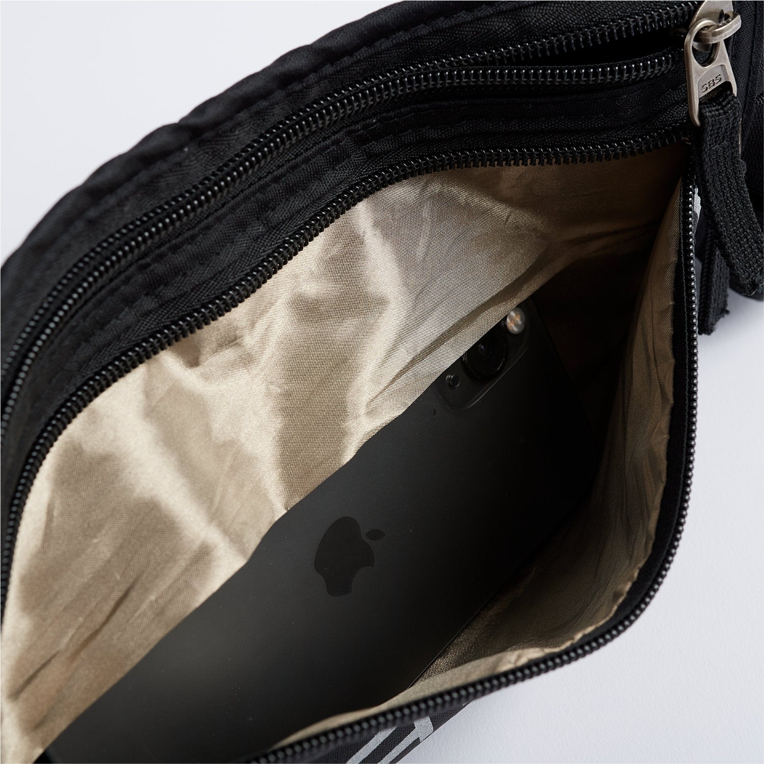 Unzip the Faraday Waist Pack – RFID Belt Bag by American Reserves to reveal a smartphone inside its black exterior with beige interior. It offers RFID blocking and EMP protection for your peace of mind.