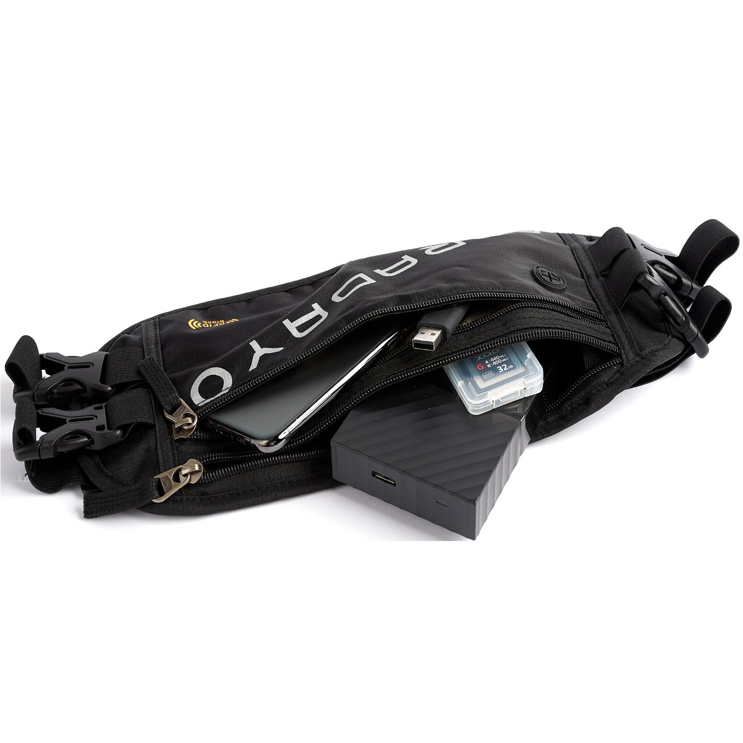 The black American Reserves Faraday Waist Pack – RFID Belt Bag is open, showing a phone, portable hard drive, SD card, and USB cable. With side buckles and RFID blocking technology, it combines style and security for your essentials. BRAVO is partially visible on it.