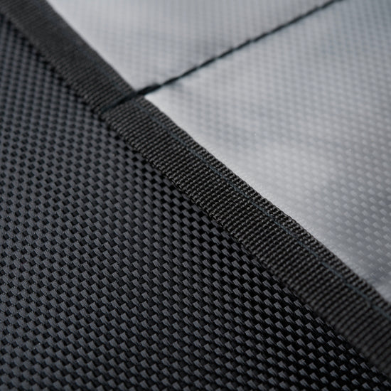 Close-up of two textured black fabrics from the XXL Forensic Faraday Laptop Jacket by American Reserves: one has a checkerboard pattern similar to RFID-blocking materials, while the other is smooth and plain.