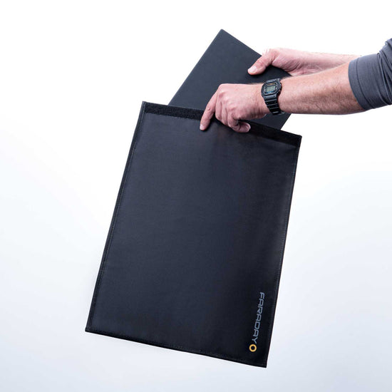 Someone slides a laptop into an American Reserves XXL Forensic Faraday Laptop Jacket (14 x 16), with the logo visible, ensuring RFID blocking and device shielding.