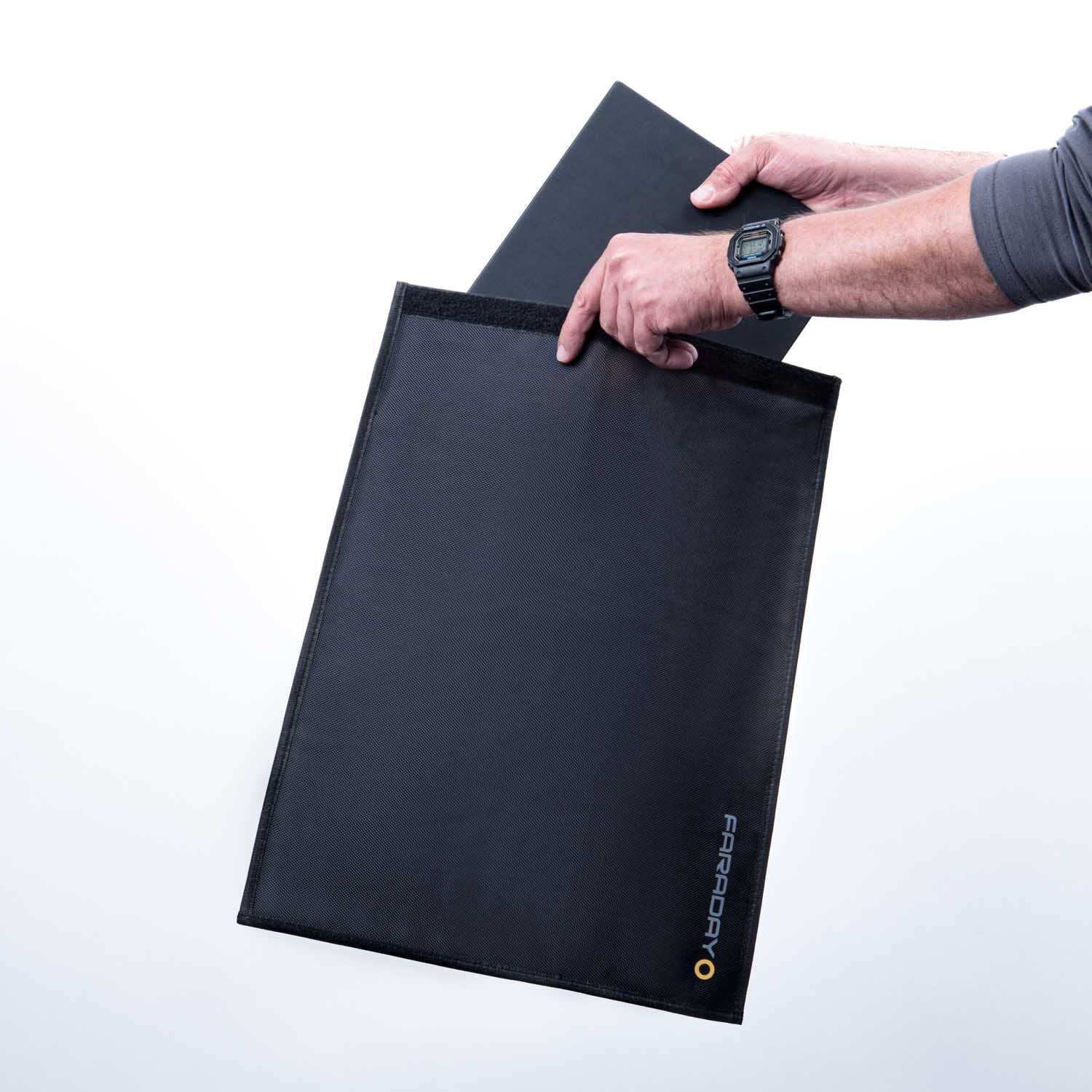 Someone slides a laptop into an American Reserves XXL Forensic Faraday Laptop Jacket (14 x 16), with the logo visible, ensuring RFID blocking and device shielding.
