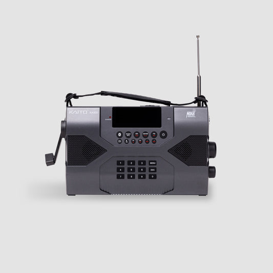 The American Reserves KA900 Voyager Max is a sleek, black receiver with a rectangular shape, digital display, buttons, and a smooth hand crank. Its telescopic antenna extends upward for emergency preparedness, ensuring connectivity.