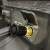 A close-up of a car interior shows an American Reserves Auxiliary EMP Vehicle Protection adapter securely inserted into the 12-volt auxiliary receptacle, providing reliable transient protection for enhanced safety.